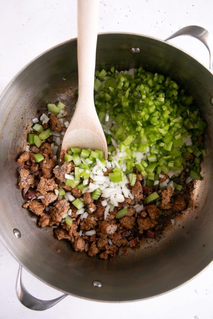 Heavy-bottomed pan filled with cooked bacon and ground pork with chopped bell pepper, jalapeno, and garlic.