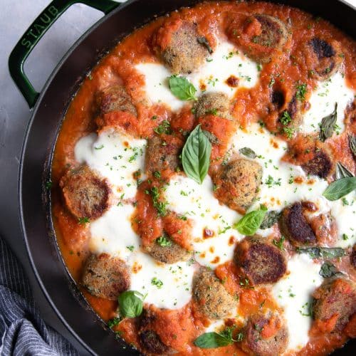 Eggplant meatballs baked with marinara sauce and cheese in a large skillet.