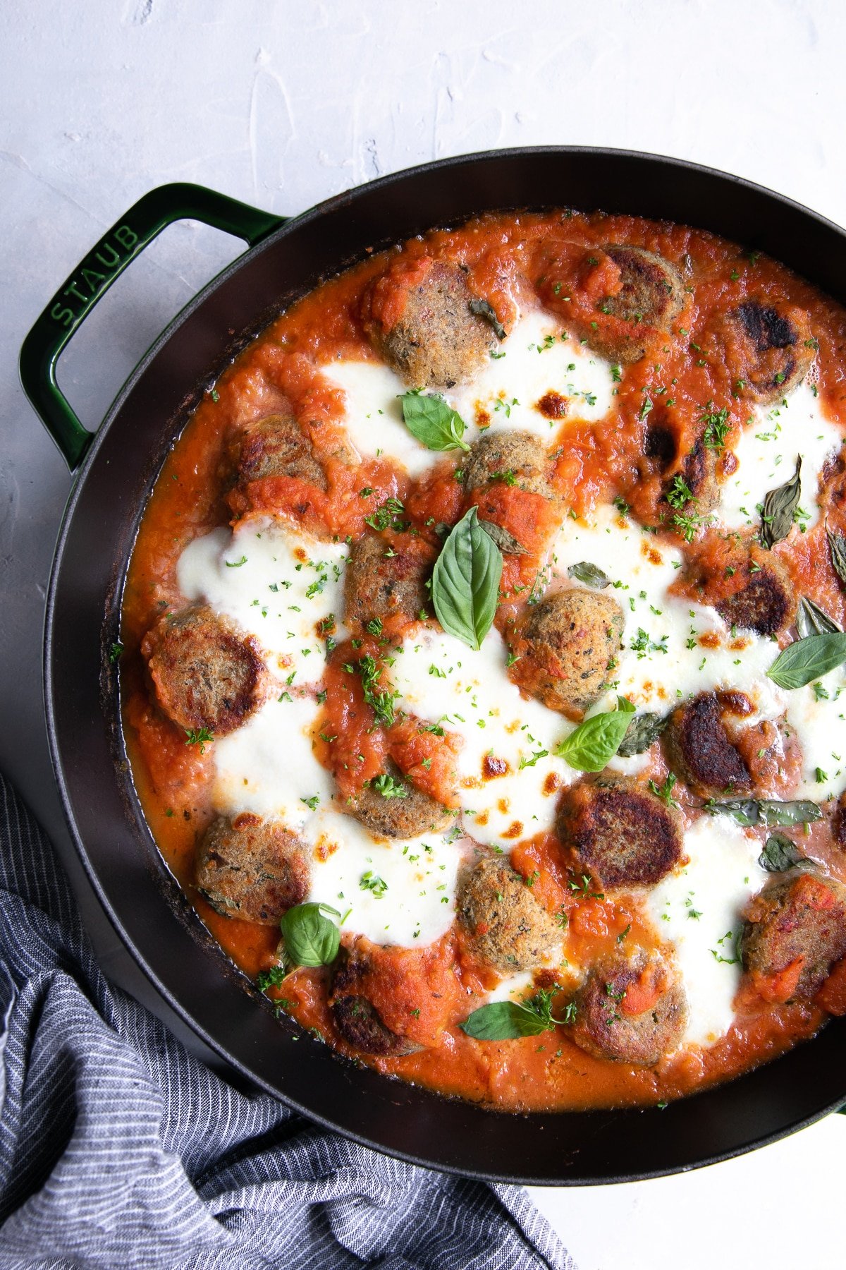 Eggplant meatballs baked with marinara sauce and cheese in a large skillet.