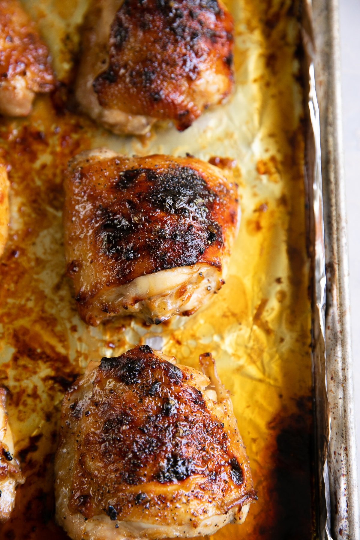 Juicy oven-baked honey soy chicken thighs on a large baking sheet.