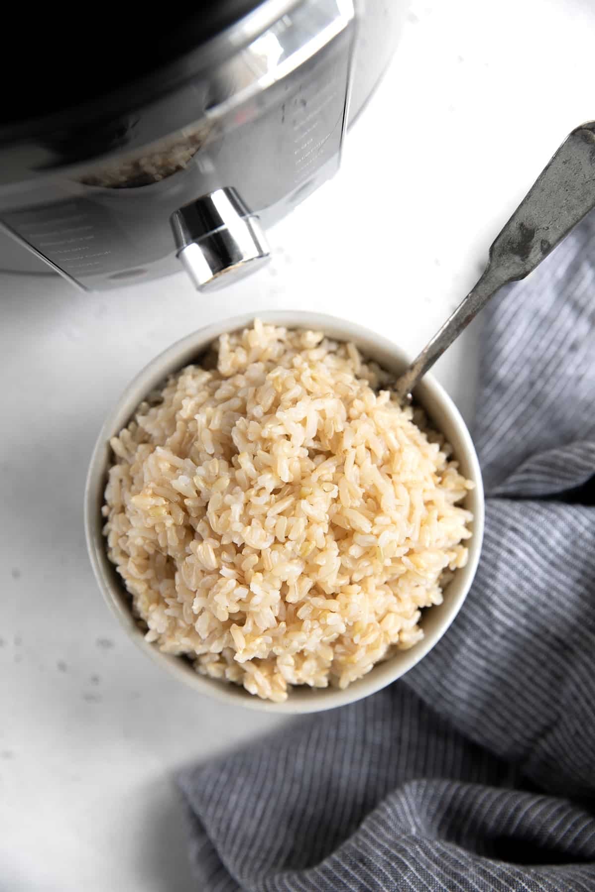 Overhead view of cooked brown rice in a small white serving bowl.