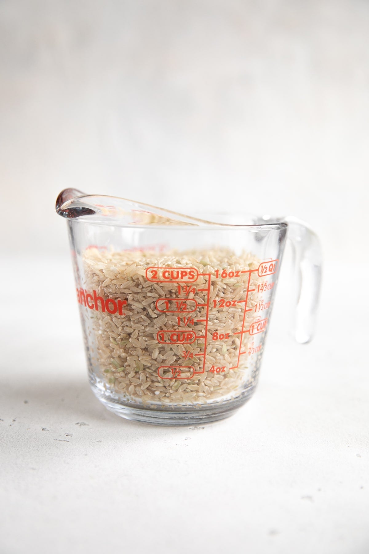 Glass measuring cup filled with long-grainbrown rice.
