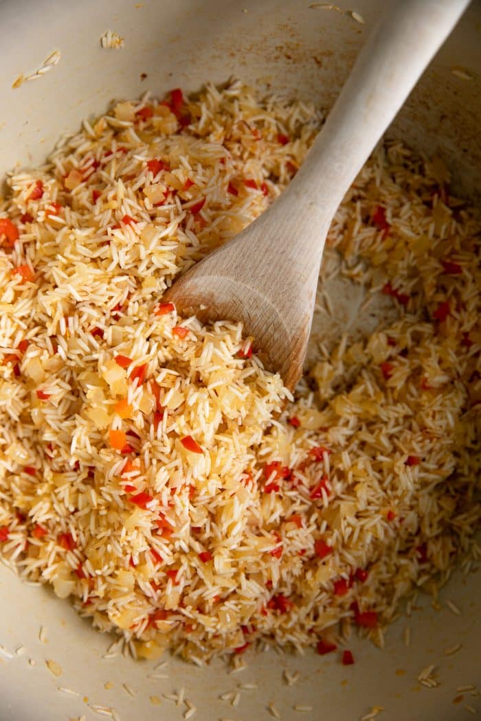 Toasting long-grain white rice with garlic, onion, and red bell pepper in a large Dutch oven over medium heat.