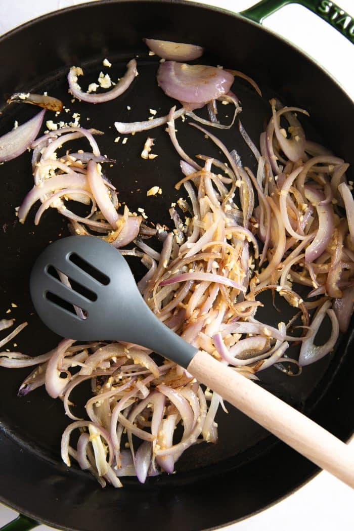Cooking sliced shallots and garlic in a large skillet.