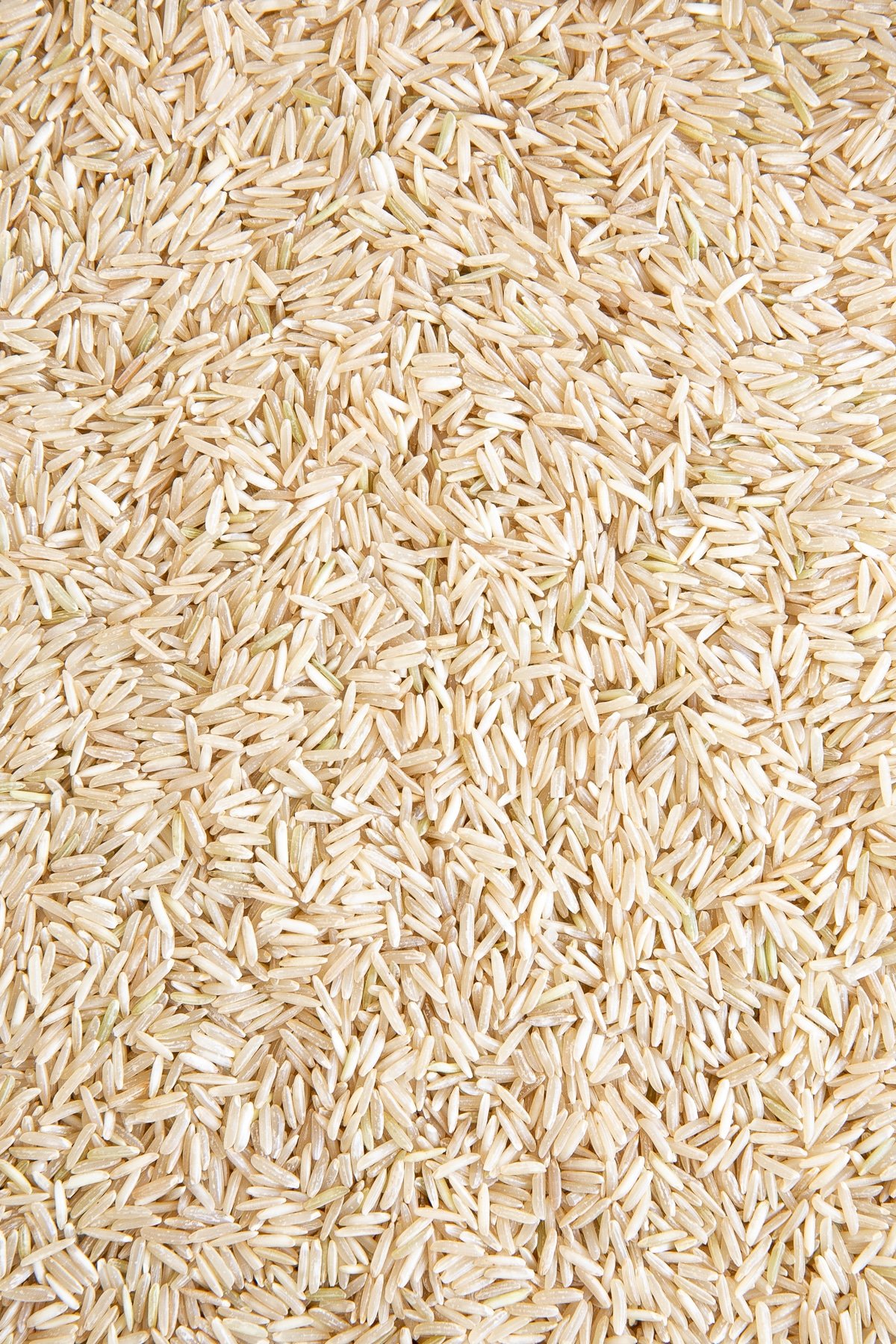 Dry, uncooked brown basmati rice spread out on a table.