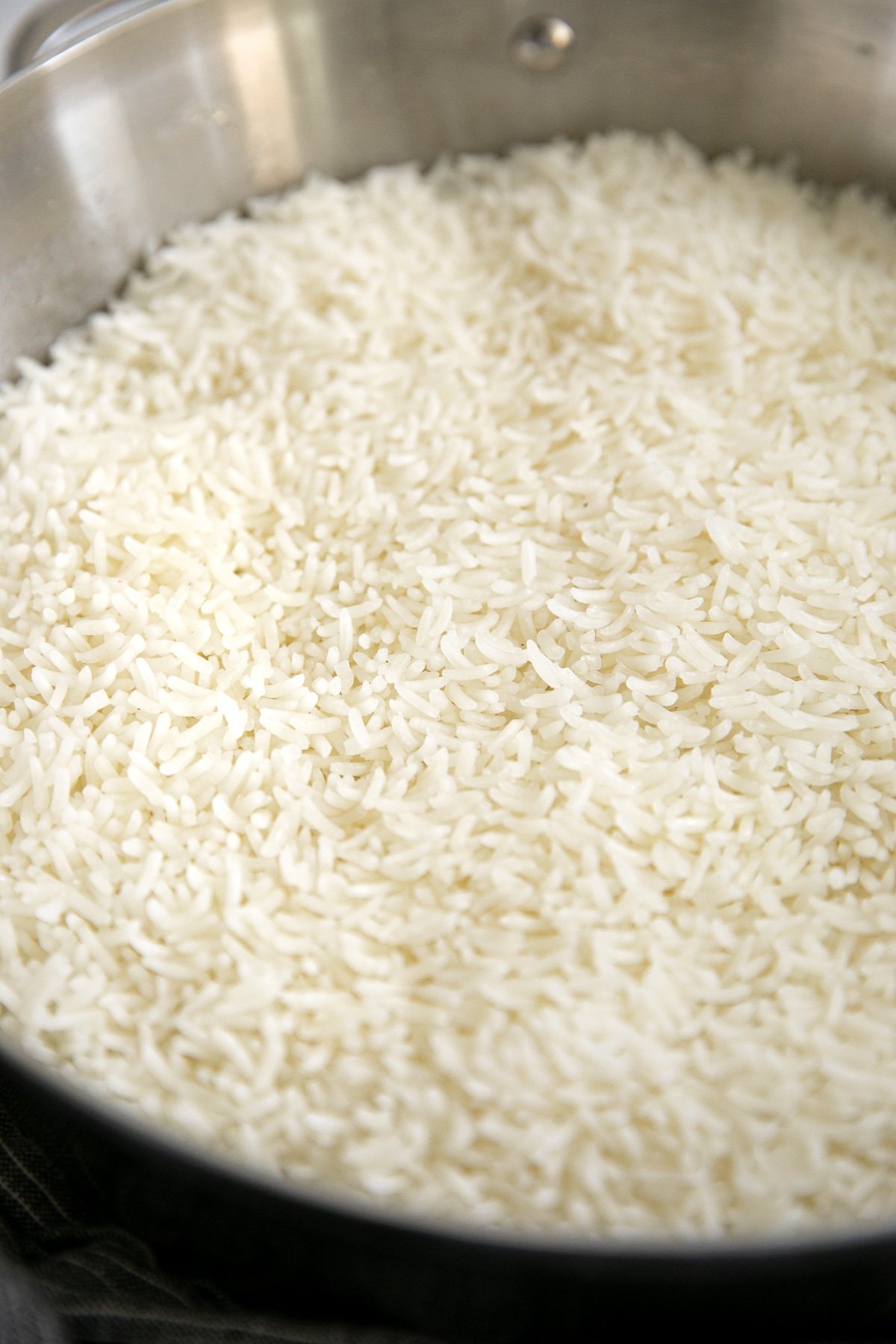 Cooked jasmine rice in a wide pot not yet fluffed.