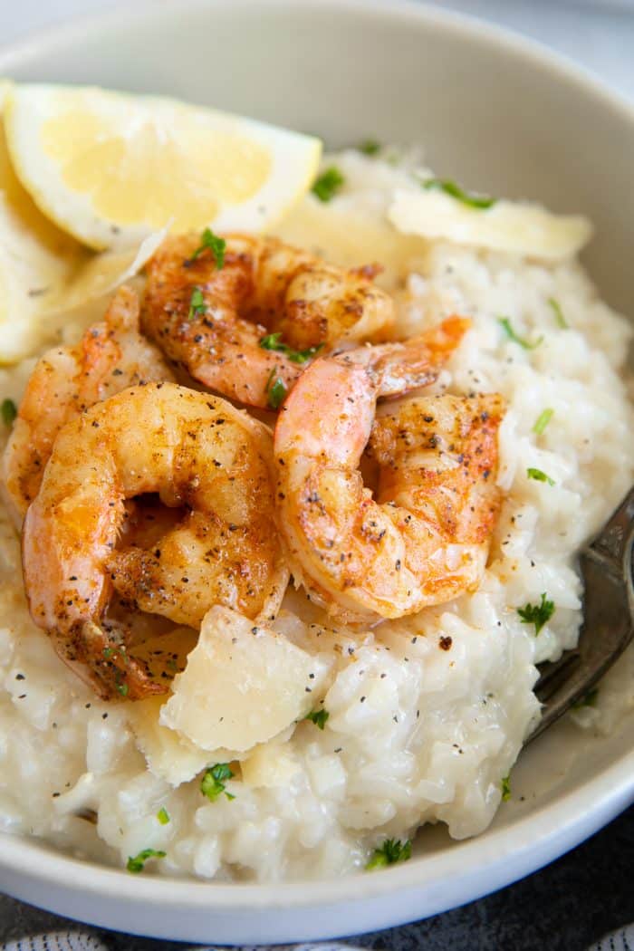 close up of white bowl of Creamy Parmesan Risotto Recipe with Shrimp with slice of lemon