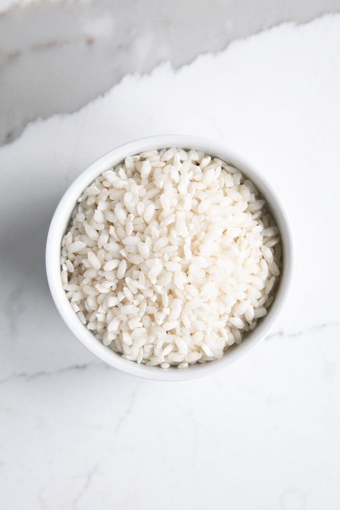 Small white bowl filled with uncooked arborio rice