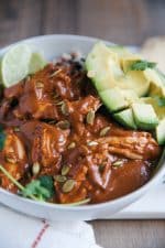 Chicken Mole with sliced avocado in a white bowl