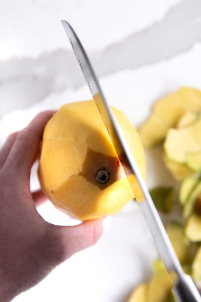 Peeled mango being sliced in half.
