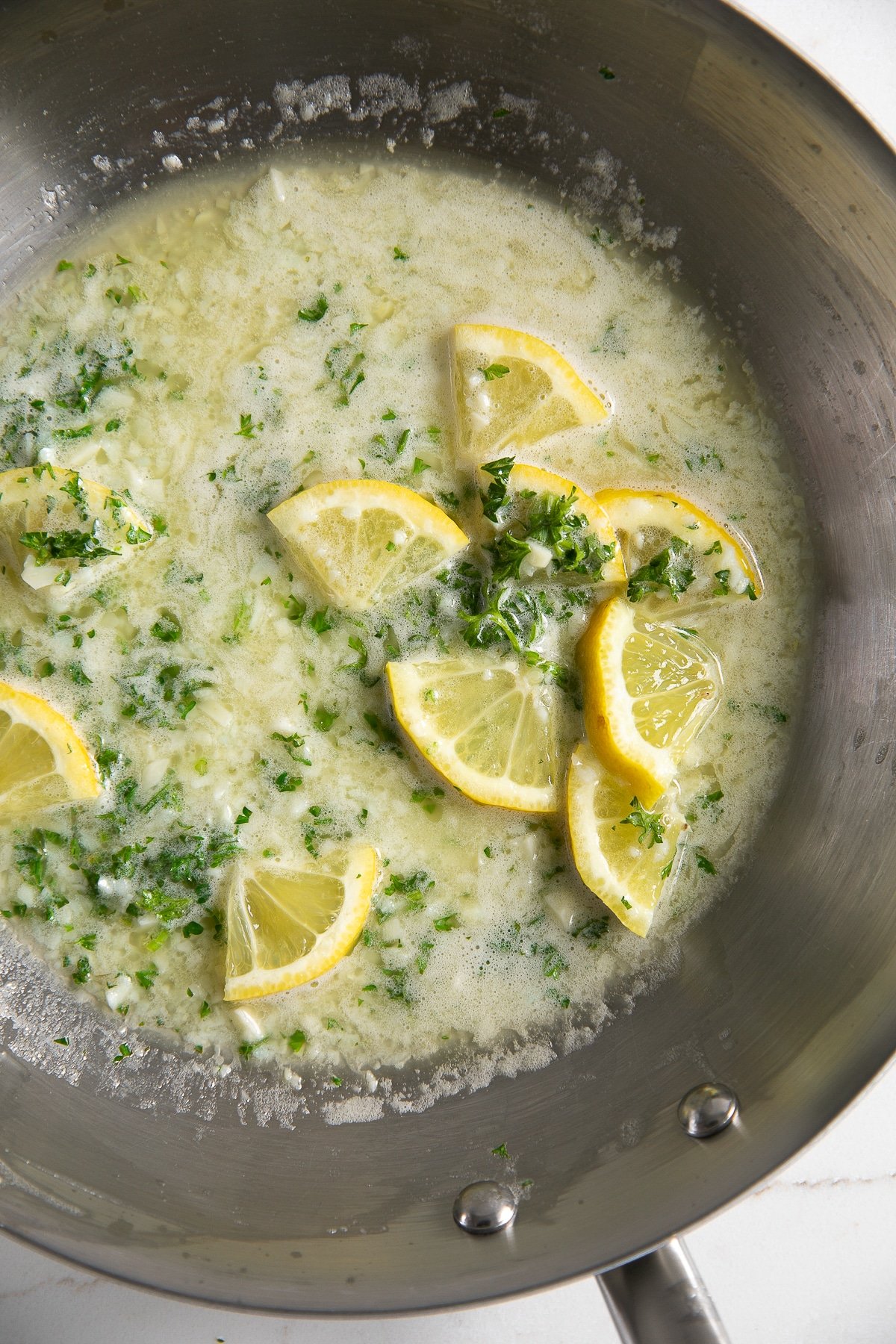 Skillet filled with melted butter, lemon juice, and minced garlic.