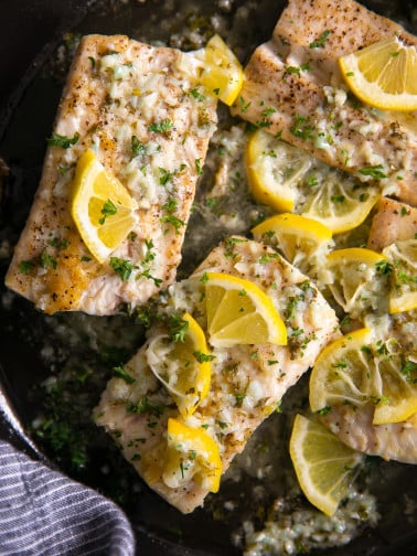 Skillet filled with fully cooked mahi mahi fillets cooked in a lemon butter sauce and garnished with fresh parsley.