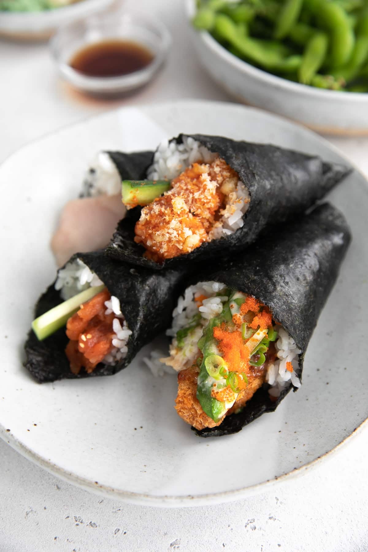 Plate filled with four sushi hand rolls