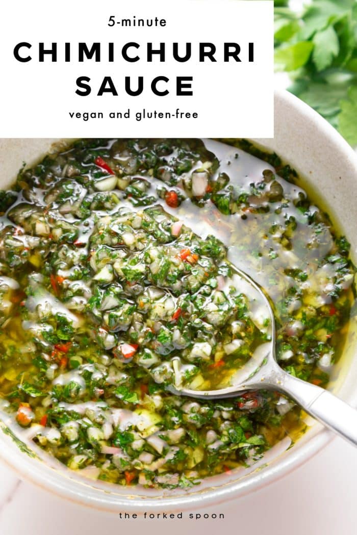 Vertical Pinterest pin with a white text box at the top and a close-up food photo underneath. The photo shows chunky green chimichurri sauce in a light beige bowl with a silver spoon scooping the sauce; visible parsley, garlic, shallot pieces, and red chile bits are suspended in olive oil, with blurred parsley leaves in the background. Text overlays read “5-minute,” large “CHIMICHURRI SAUCE,” and “vegan and gluten-free,” with “the forked spoon” at the bottom.