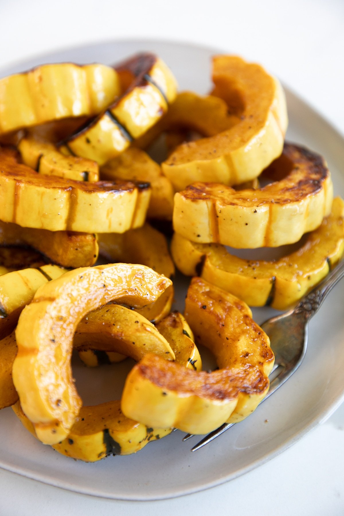 White serving plate filled with oven-roasted delicata squash.