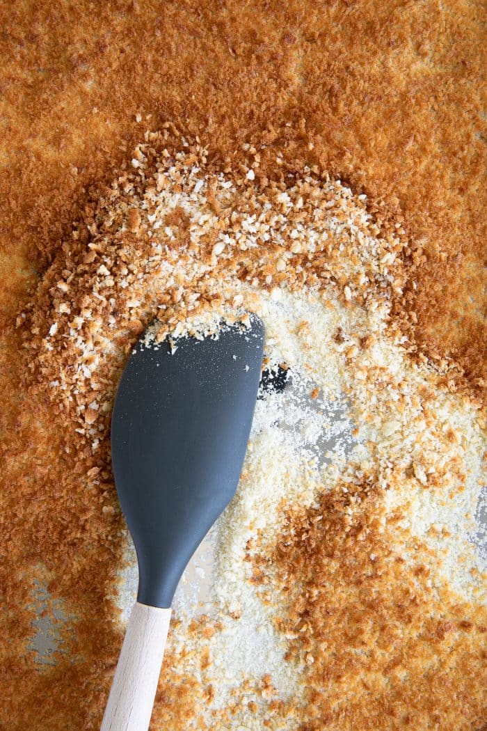 Panko breadcrumbs spread over a large baking sheet after toasting in the oven.