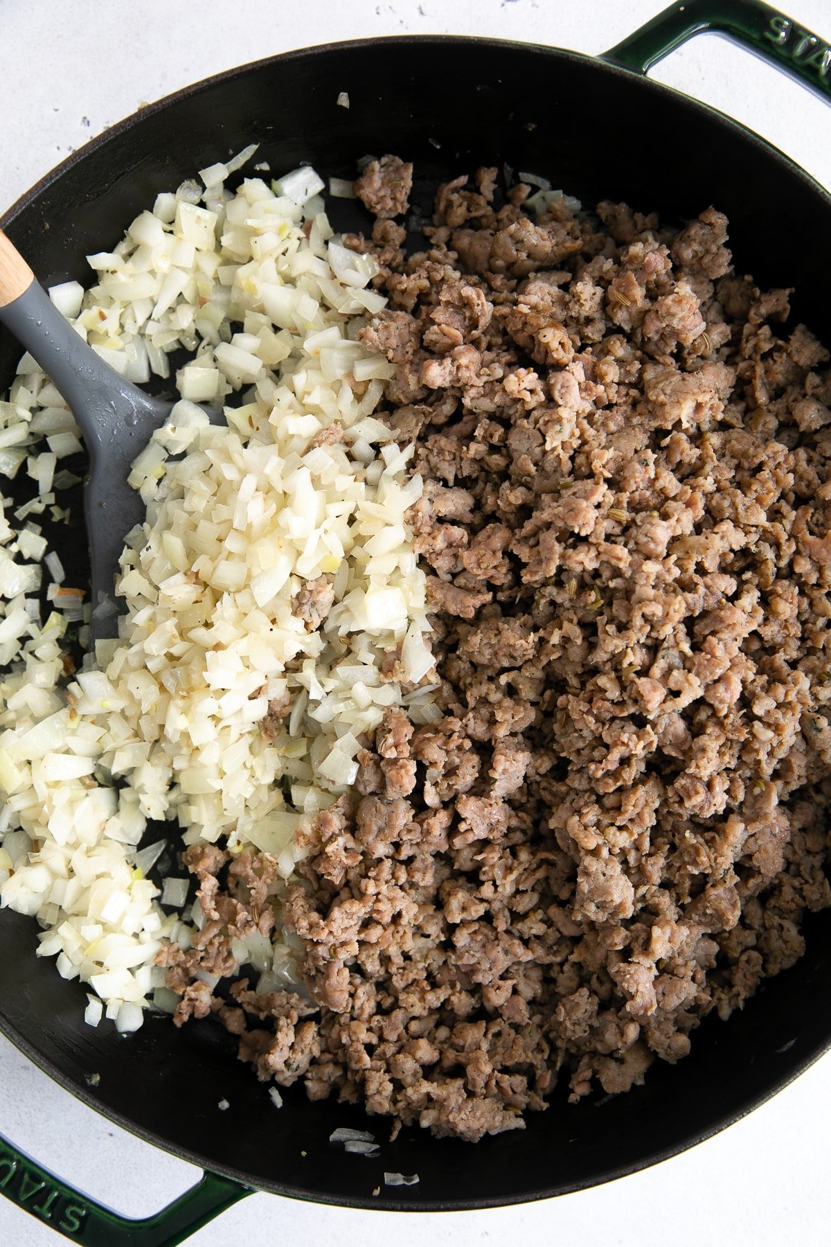 Combining softened onions and garlic with browned cooked Italian sausage crumbles.