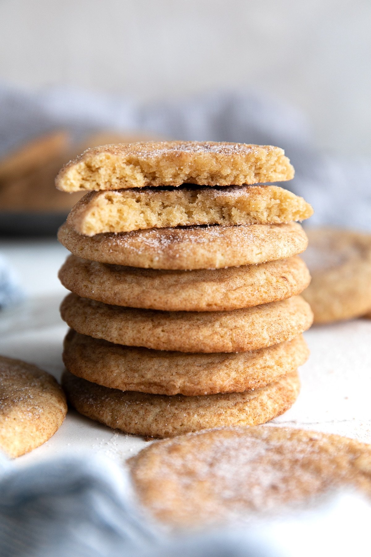 Stack of five snickerdoodle cookies topped with one snickerdoodle broken in half.