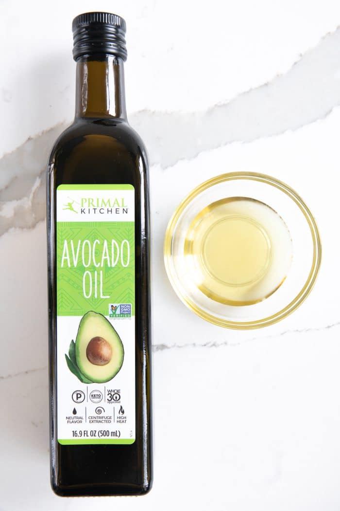 Bottle of avocado oil with a small sample in a glass dish to its left