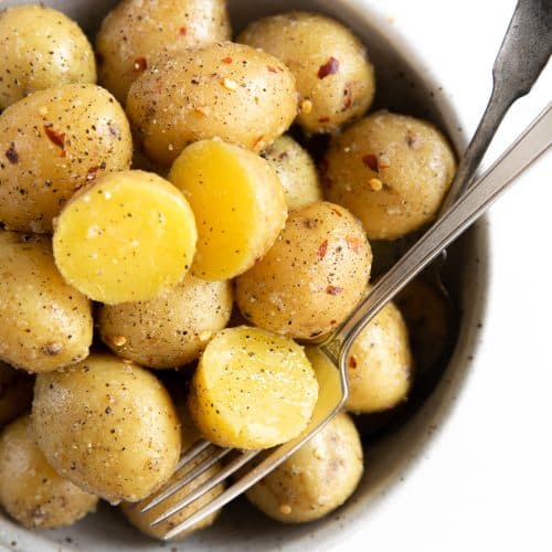 Round serving bowl filled with small yellow boiled potatoes.