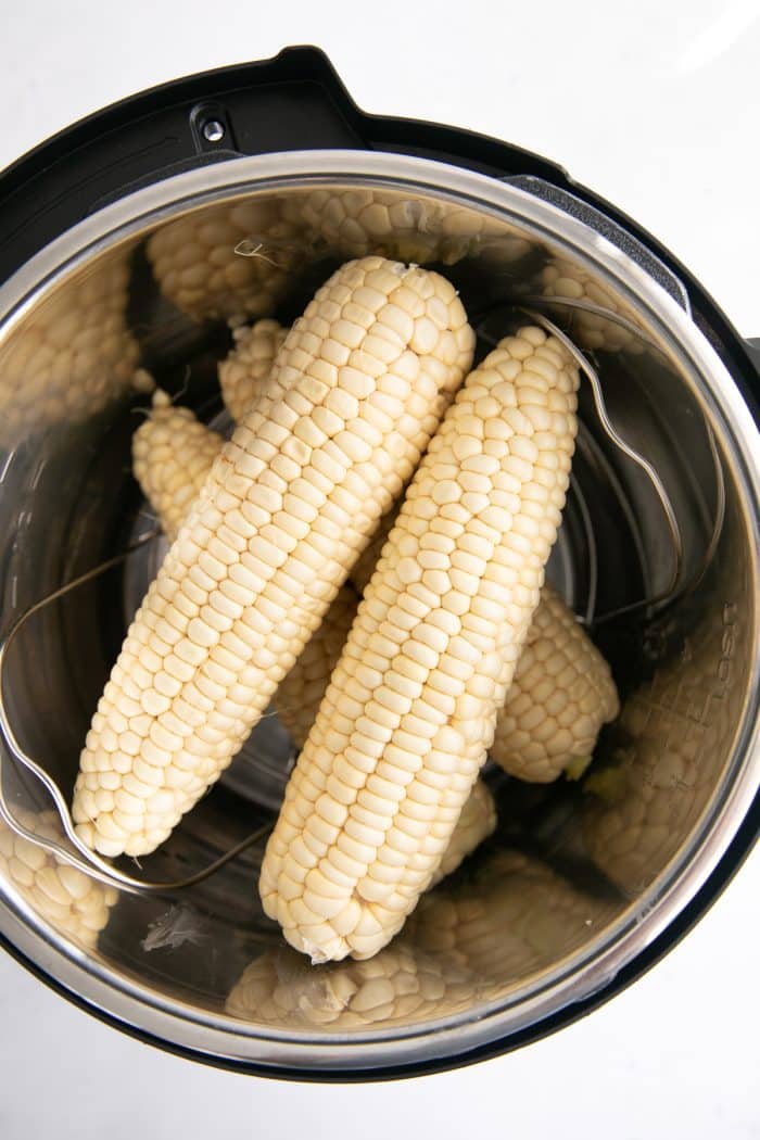 Four uncooked corn on the cob in the Instant Pot.