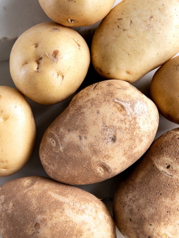 Whole raw Yukon gold potatoes and Russet potatoes.