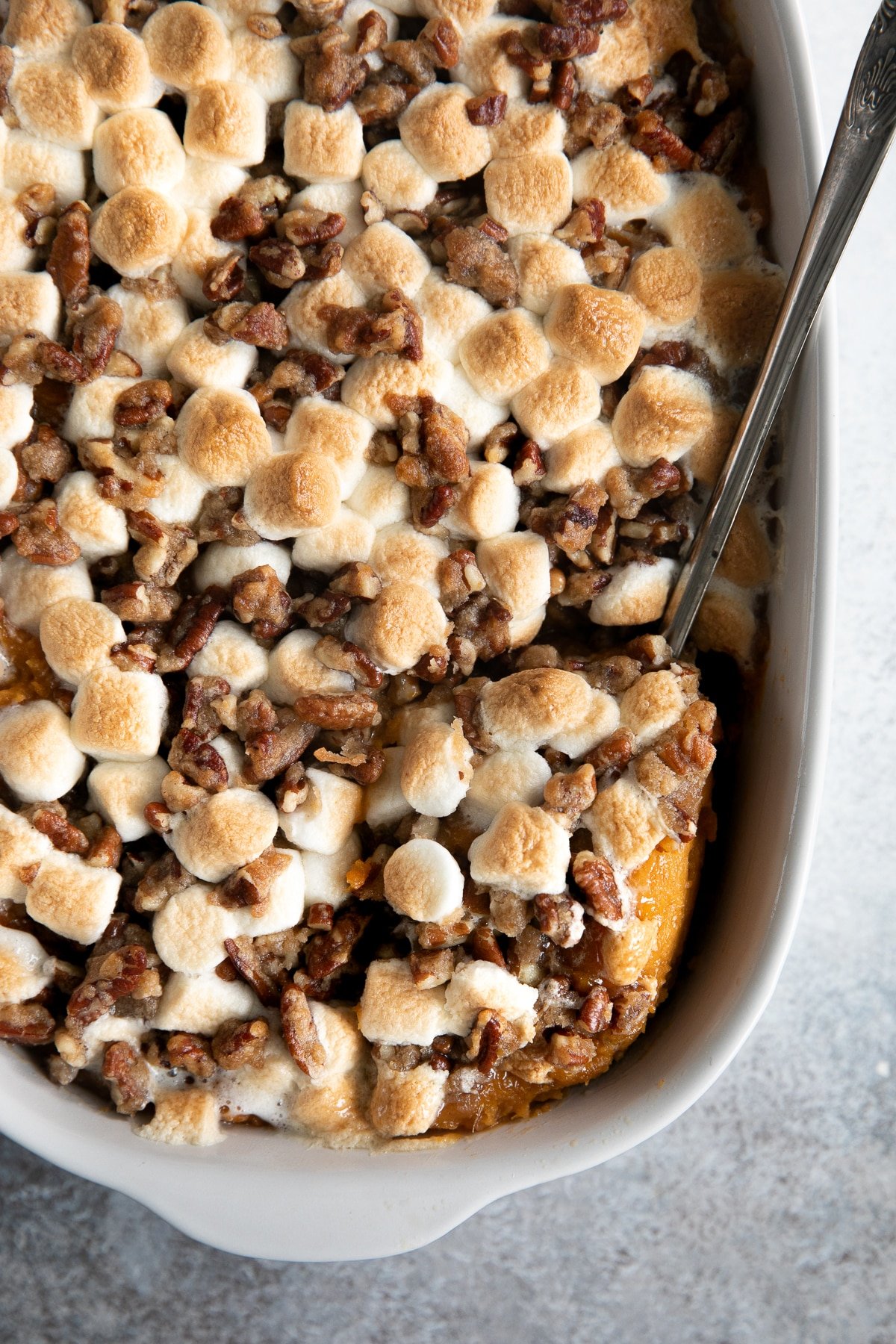 Cooked sweet potato casserole topped with chopped pecans and marshmallows