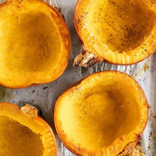 Cooked pumpkins on a baking sheet seasoned with salt and pepper