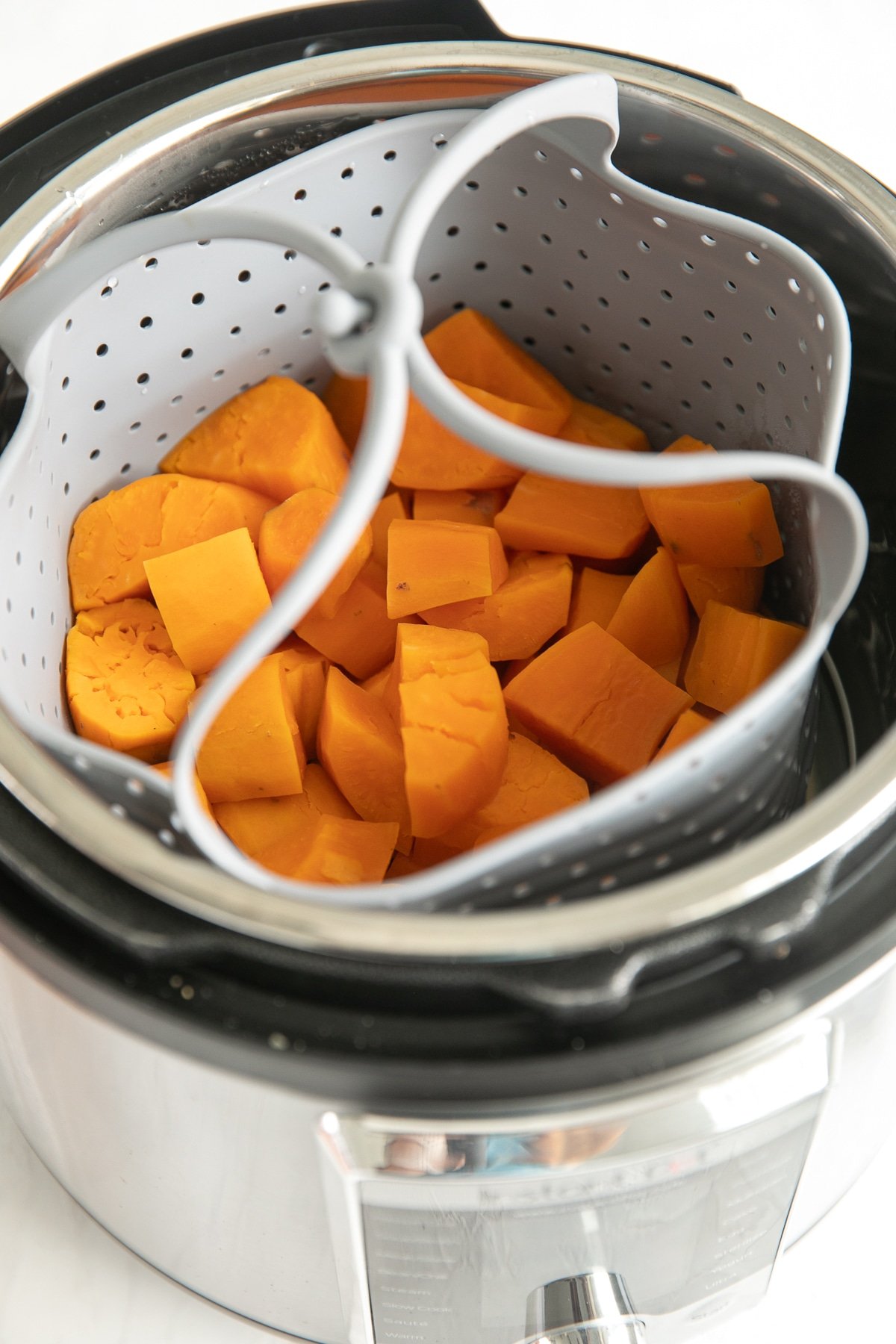 Peeled and chopped sweet potatoes in an Instant Pot steamer steamer basket.