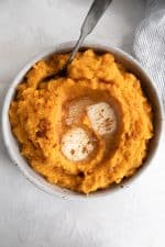 Mashed sweet potatoes cooked in an Instant Pot served in a round, shallow bowl and topped with extra butter.
