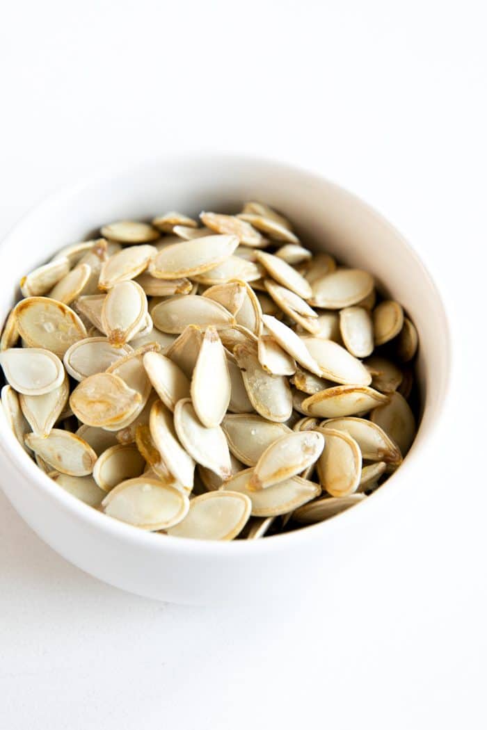 Small white bowl filled with homemade roasted pumpkin seeds