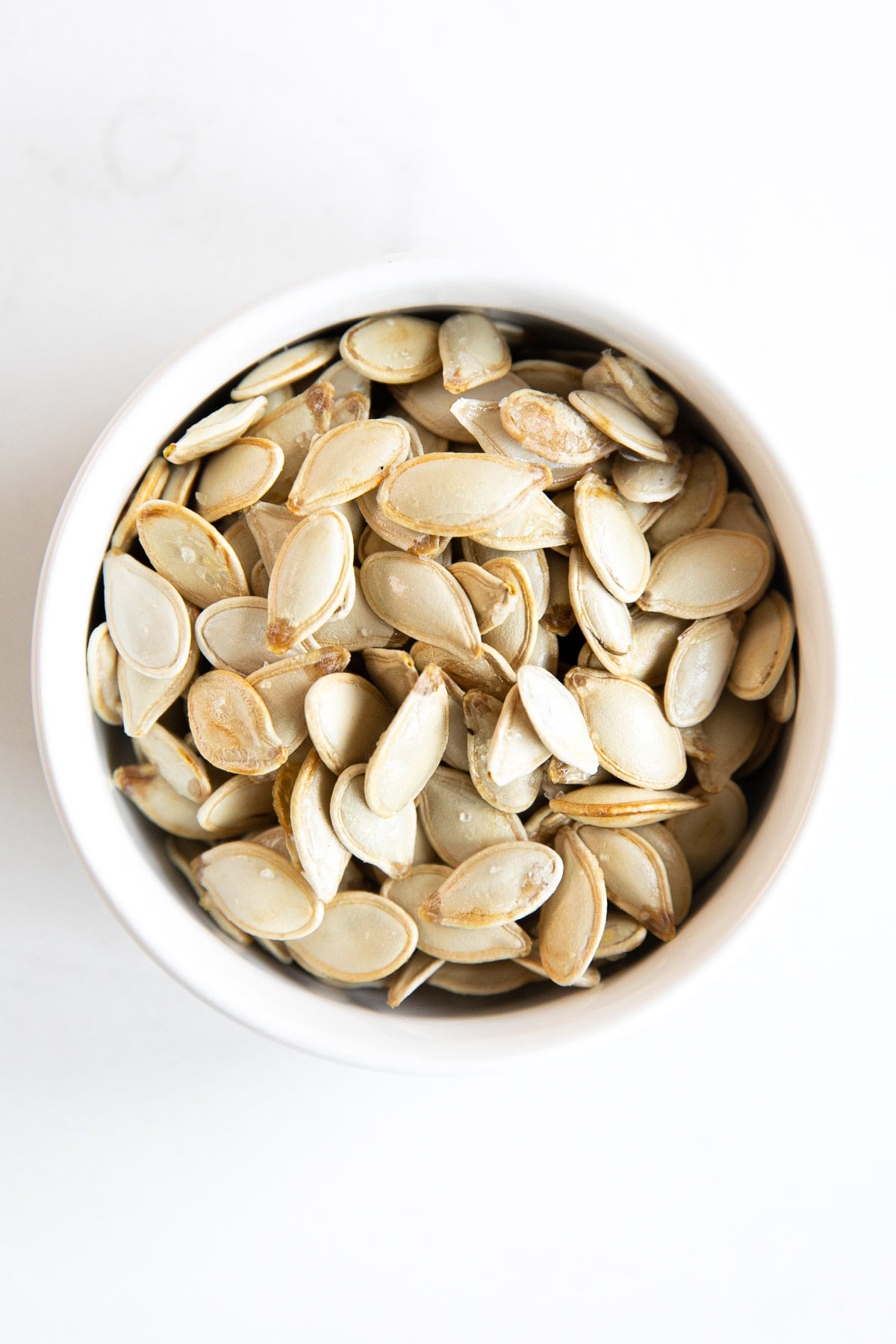 Small white bowl filled with homemade roasted pumpkin seeds