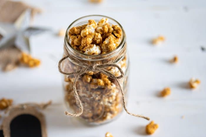 Gingerbread caramel corn in a glass mason jar wrapped with twine.