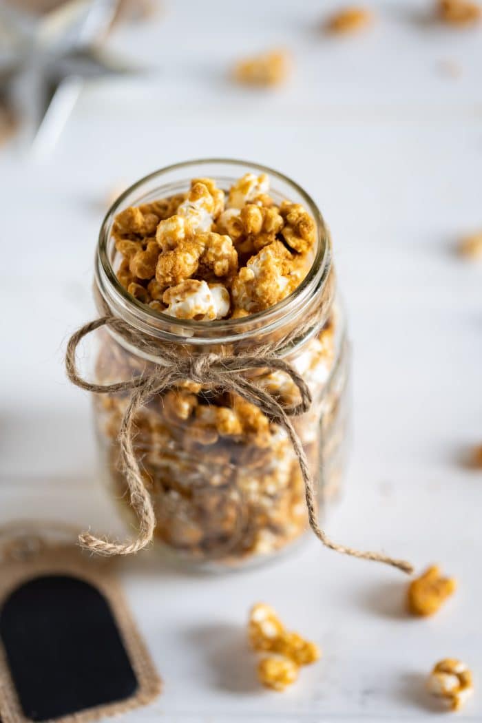Gingerbread caramel corn in a glass mason jar wrapped with twine.