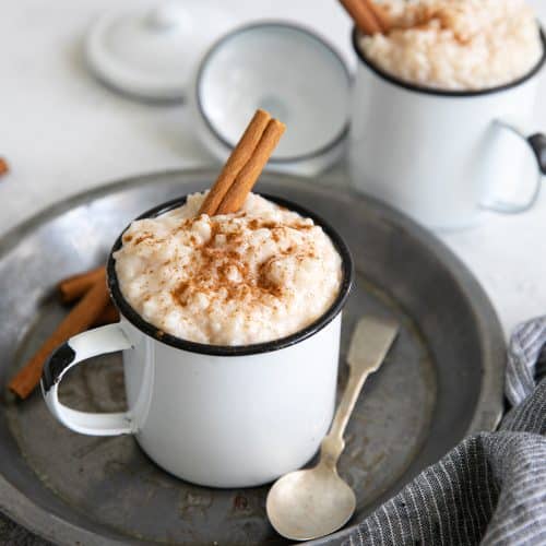 Small mug filled with arroz con leche and garnished with ground cinnamon.
