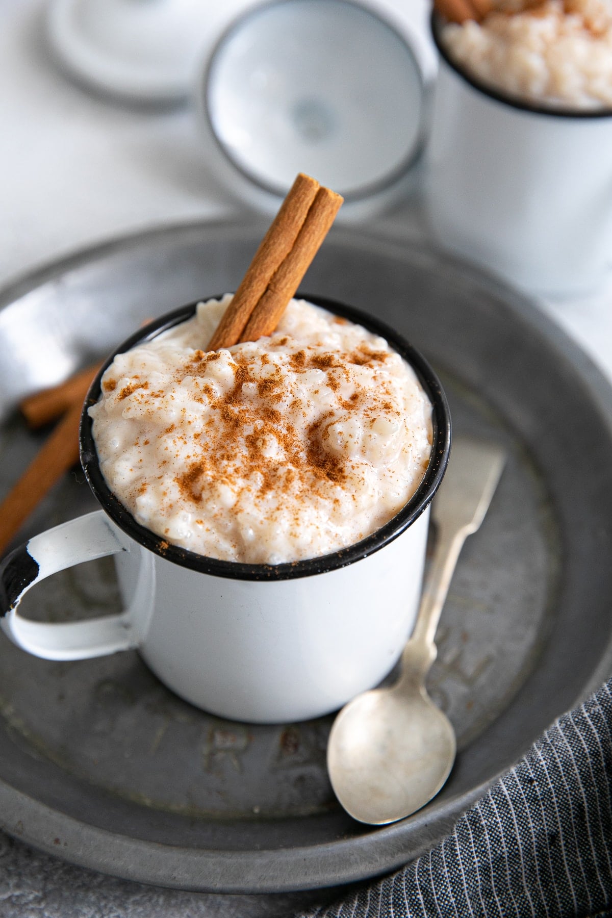 Small mug filled with arroz con leche and garnished with ground cinnamon.