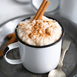 Small mug filled with arroz con leche and garnished with ground cinnamon.