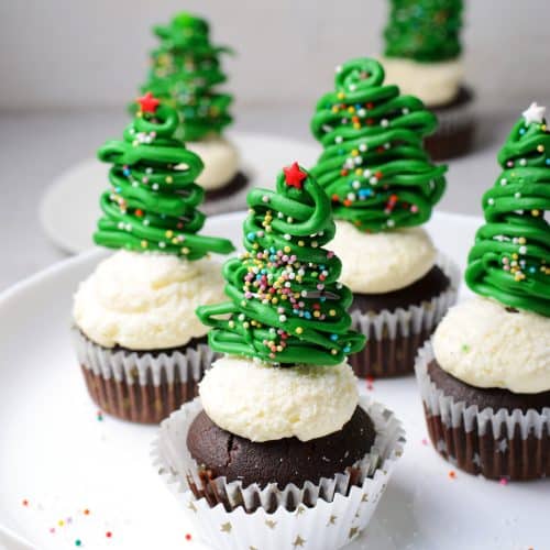 Cake stand filled with four Chocolate cupcakes with vanilla buttercream frosting and topped with a chocolate christmas tree topper.