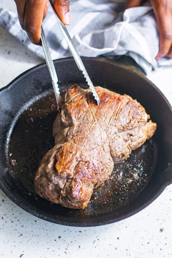 Searing beef tenderloin in a large cast-iron skillet.