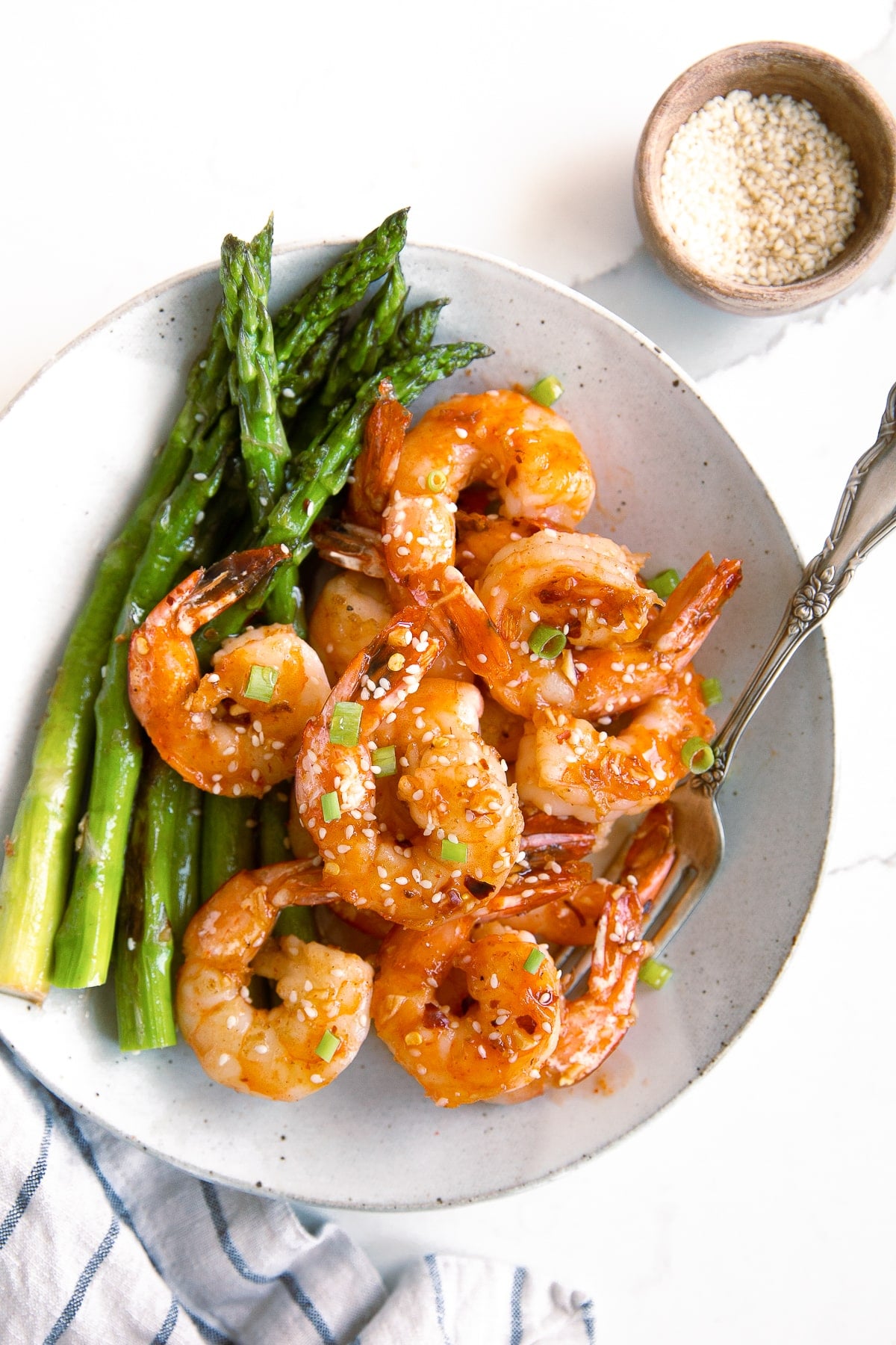 White plate filled with cooked asparagus spears and Honey Sriracha Shrimp