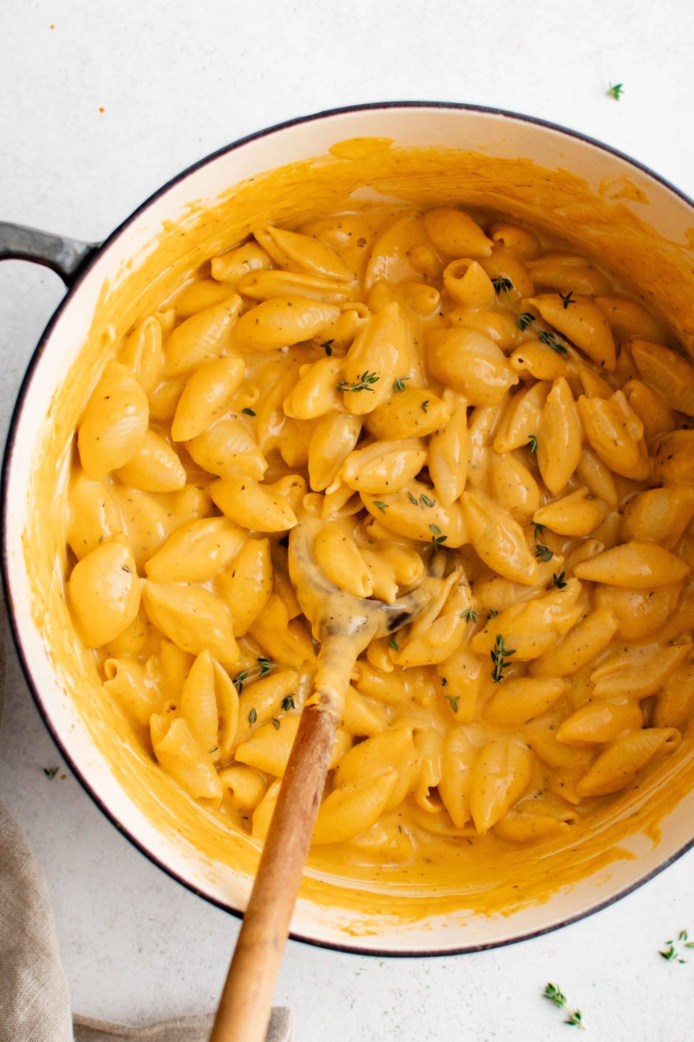 Finished mac and cheese in a Dutch oven topped with fresh thyme