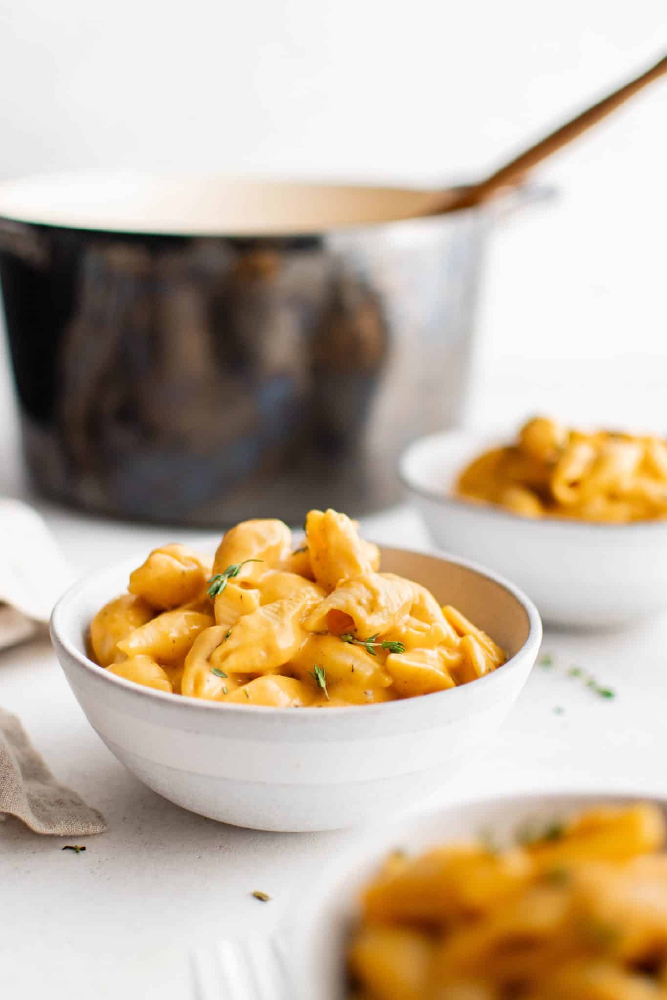 Bowl of creamy butternut squash mac and cheese with thyme garnish.