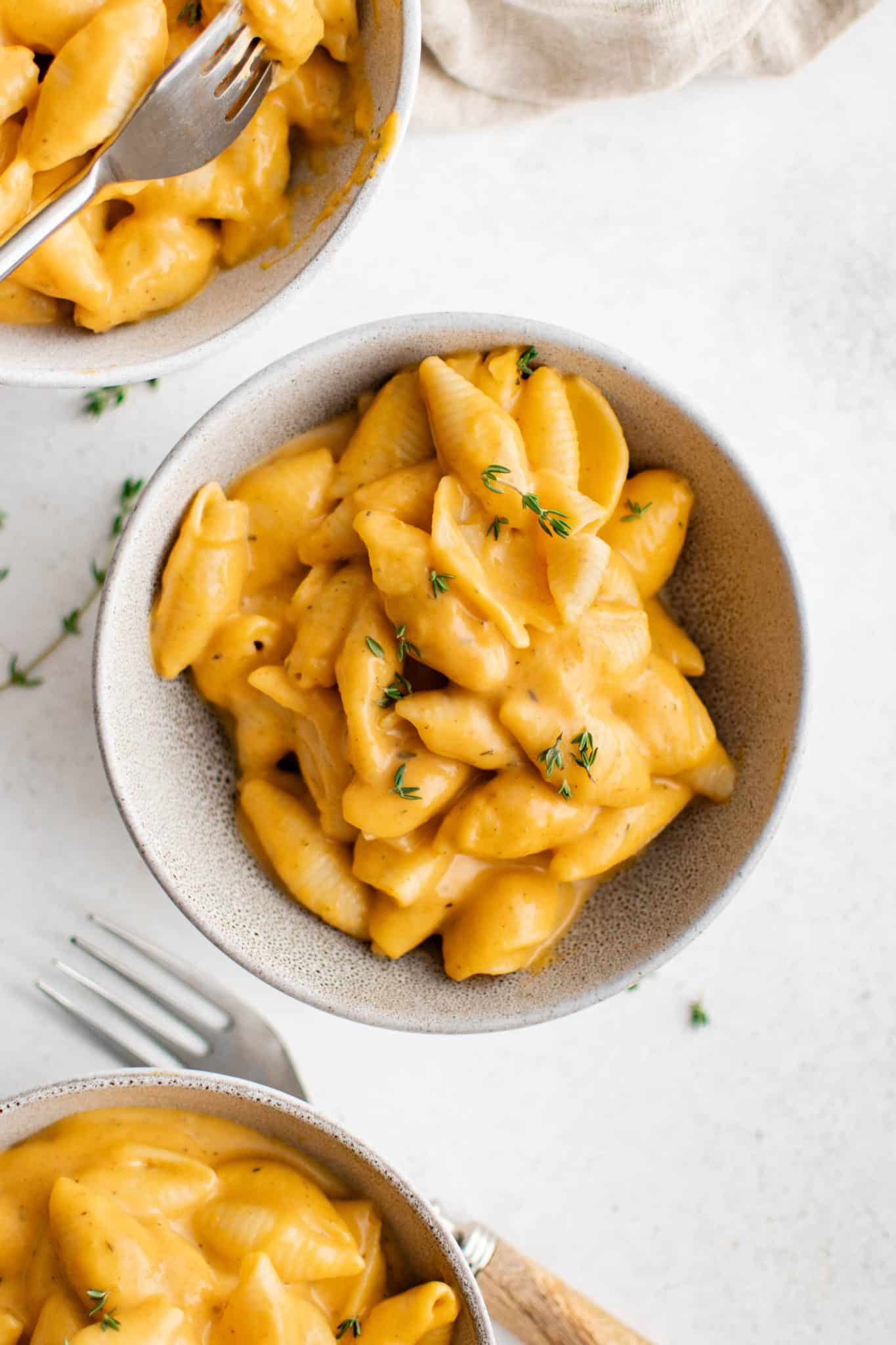 Overhead shot of three bowls of butternut squash mac and cheese with forks.