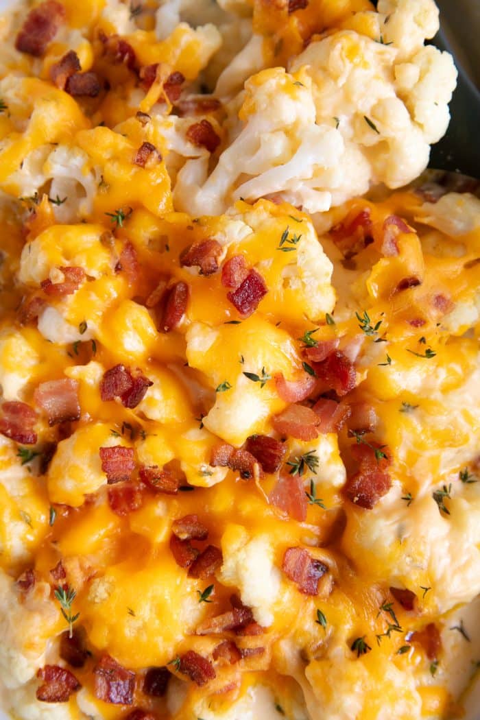 Close up image of homemade cauliflower bake topped with cheddar cheese and bacon bits.