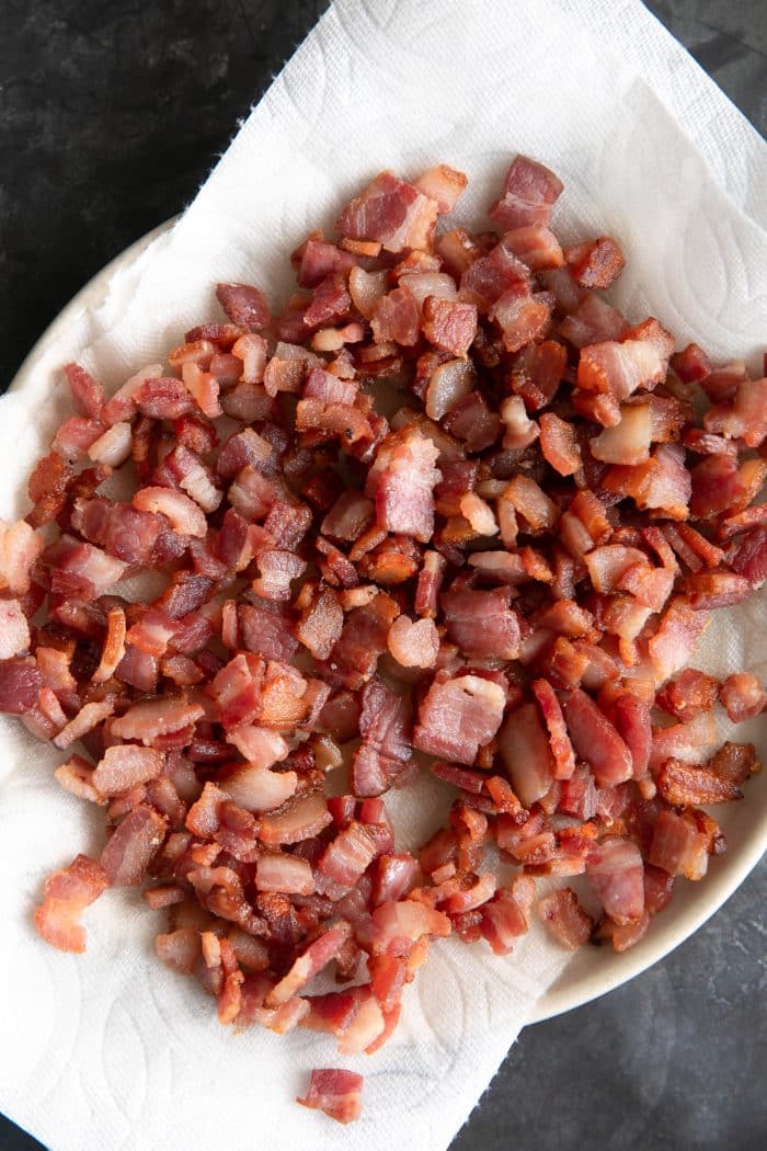 Plate lined with paper towels and filled with cooked bacon bits.