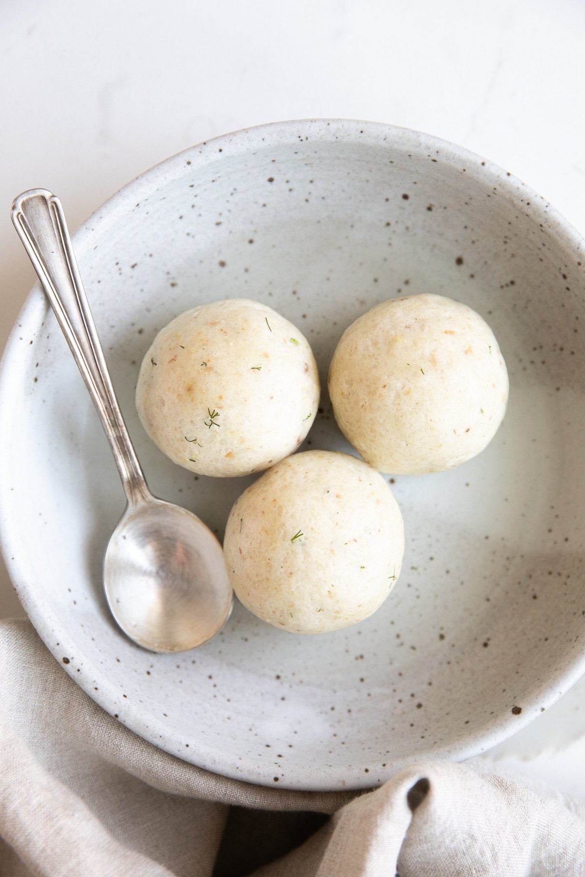 Shallow bowl filled with three perfectly cooked matzo balls.