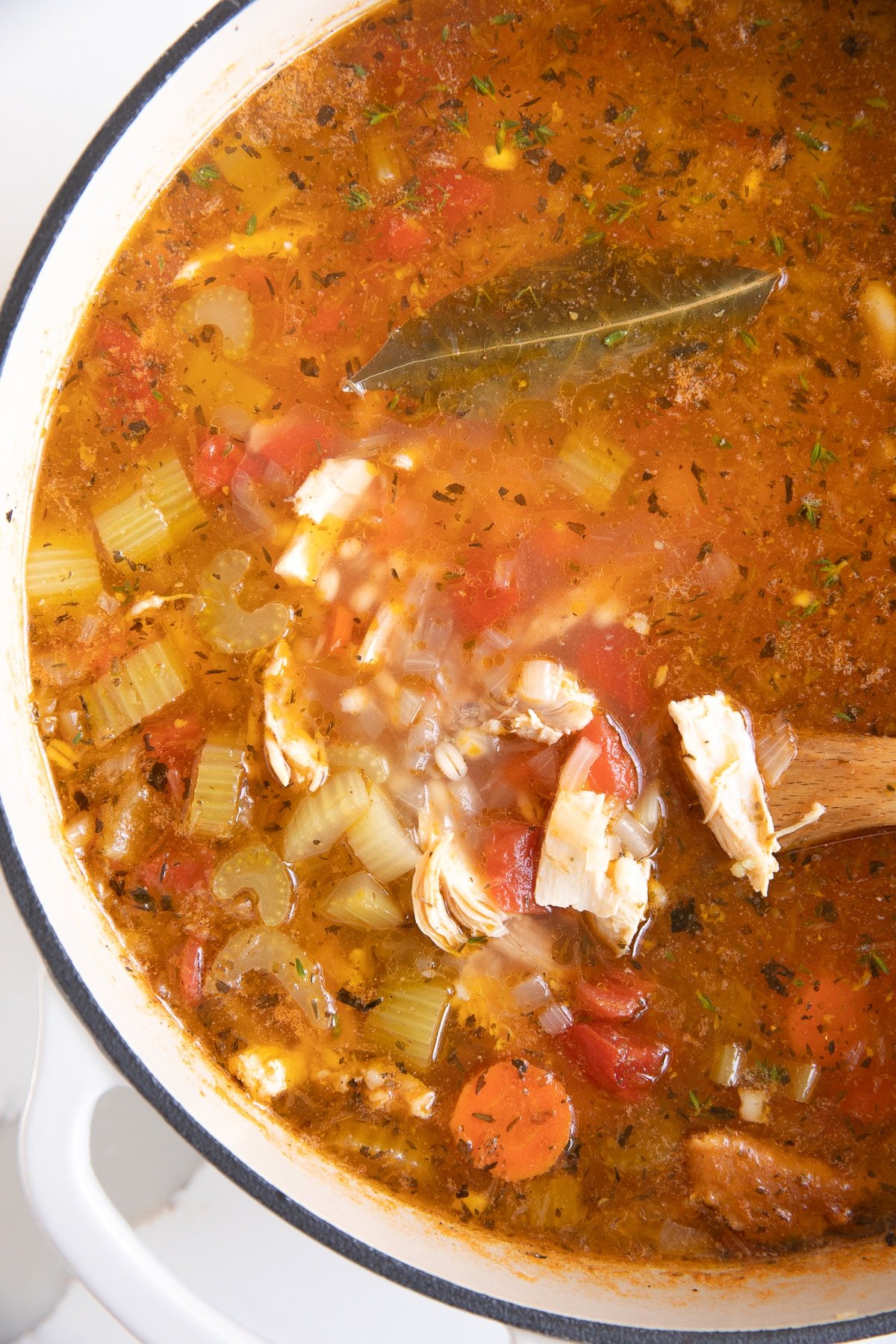 Large Dutch oven filled with simmering Thanksgiving leftover turkey soup with veggies and barley.