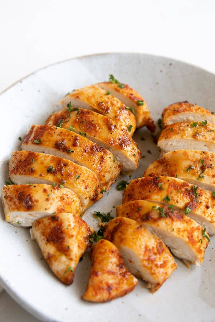 Two sliced air fryer chicken breasts on a homemade ceramic serving plate.