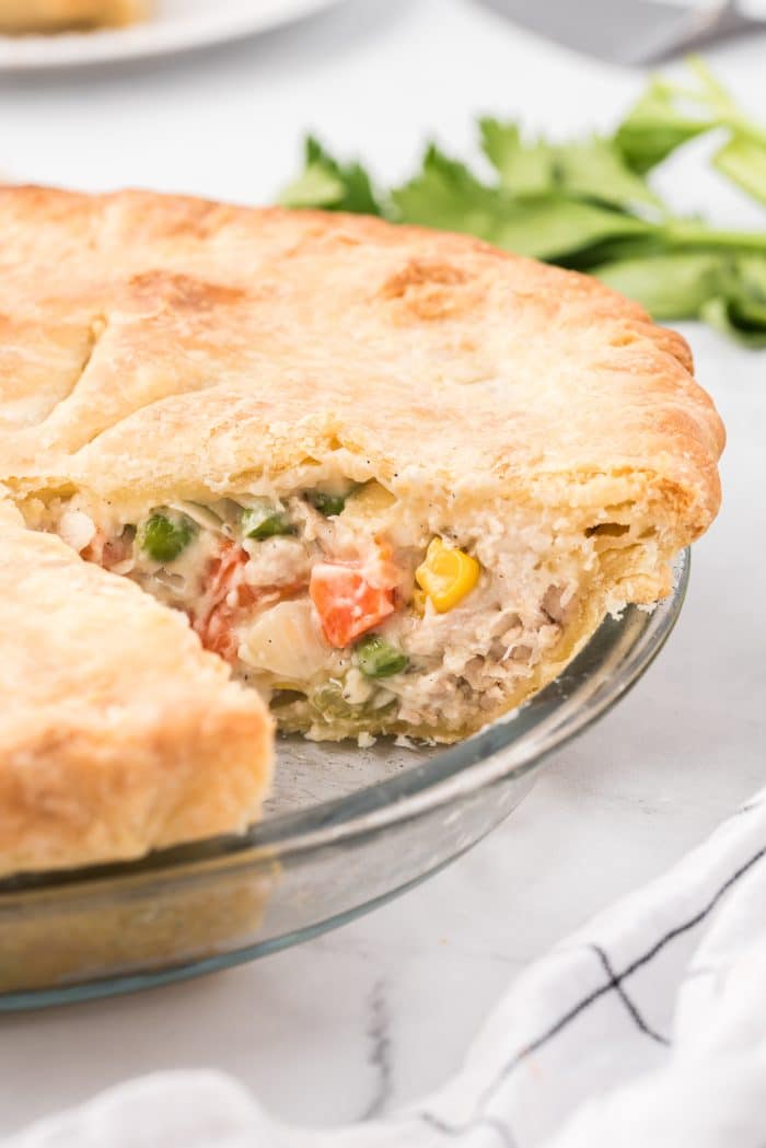 Side angle image of baked chicken pot pie with a small slice removed.