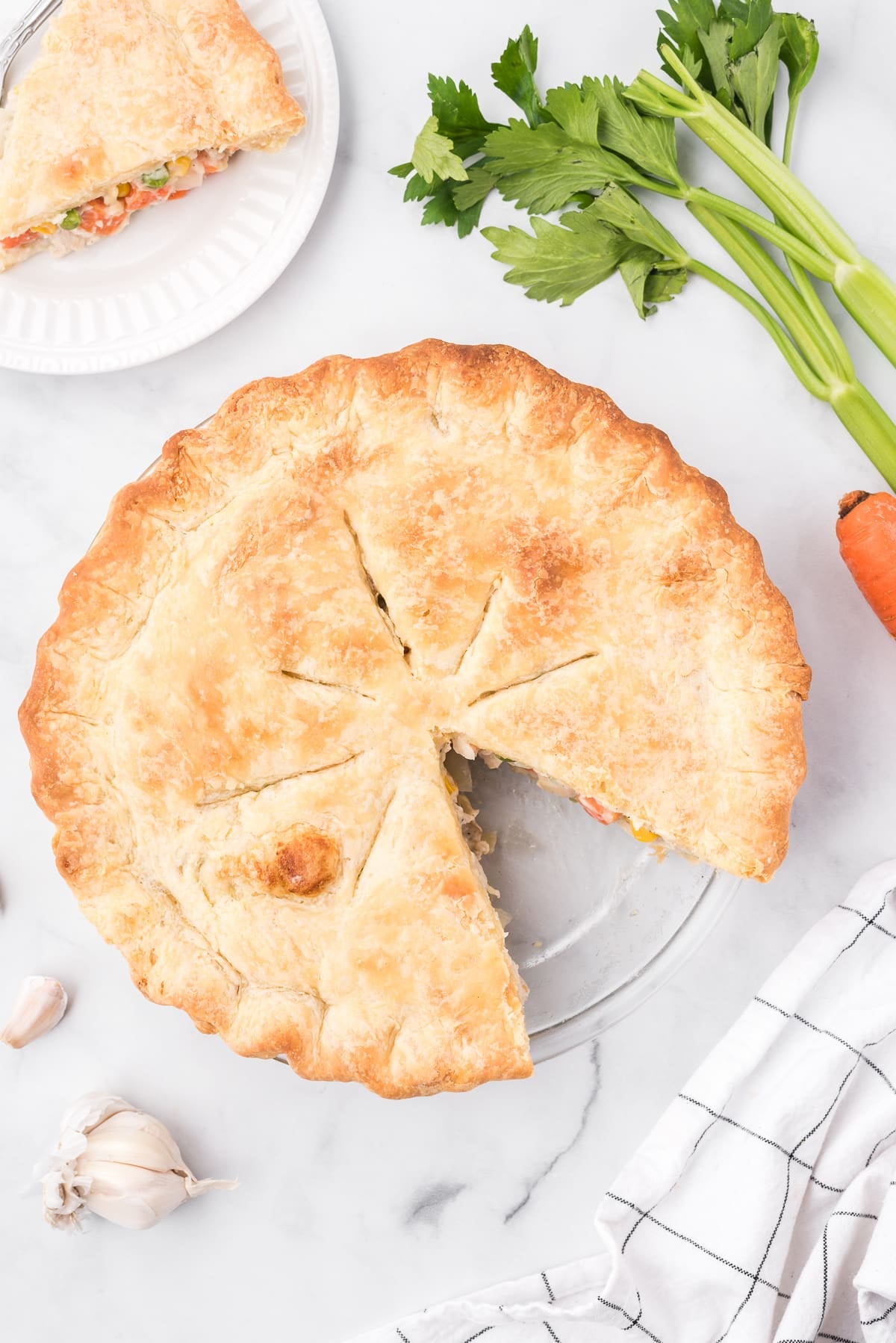 Overhead image of a chicken pot pie in a pie dish with one single sliced removed.